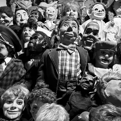 Black and white photograph of an extensive collection of ventriloquist dummy heads and puppet faces arranged together, representing various character types and eras at Dreamfactory museum in Degersheim