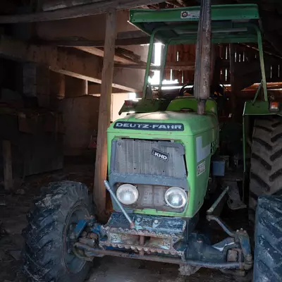 Green Deutz-Fahr tractor parked inside a wooden barn