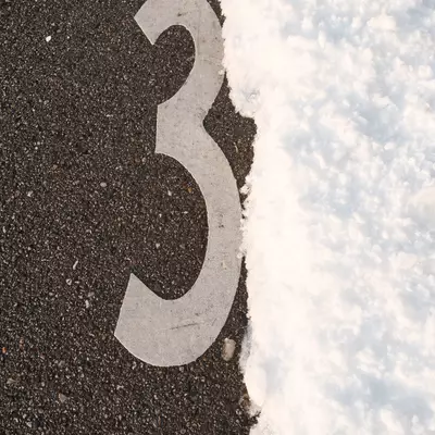 White mustache symbol painted on dark asphalt next to snow