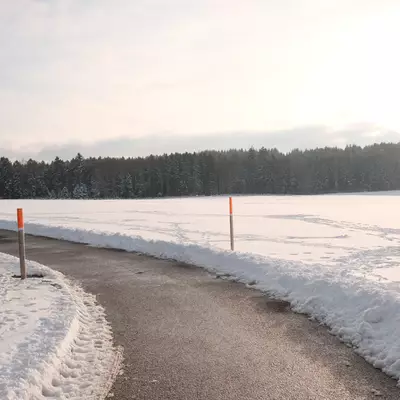 Cleared road cutting through a snowy landscape with orange poles marking the edges