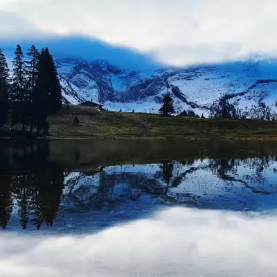 Le lac photo est au premier plan. On peut voir le glacier 3000 en deuxième plan. Les montagnes se réfléchissent à la surface du lac.