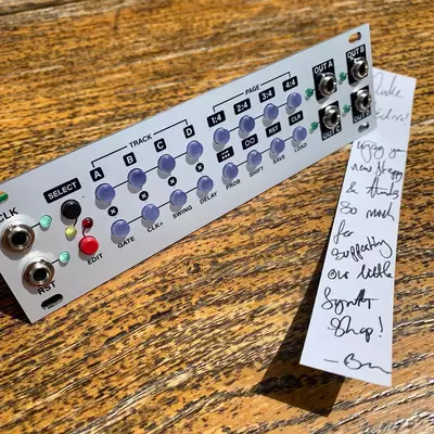 A white Intellijel Steppy sequencer module sits on a wooden surface next to a handwritten note listing setup instructions and equipment details in blue ink.
