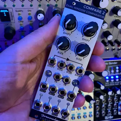 A hand holds a light gray Eurorack module labeled 
