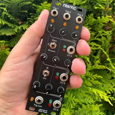 A hand holds a black Eurorack synthesizer module labeled 