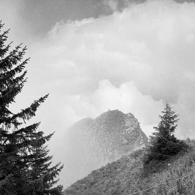 A misty black and white image capturing the silhouette of a mountain at Grand Chamossaire, with a barely visible ibex on the ridge.