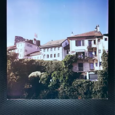 Old town of Moudon with colorful traditional Swiss houses on hillside, captured on vintage film