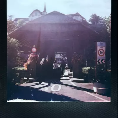 Entrance to Moudon's old wooden bridge over the Broye river, with 30 km/h speed limit signs and church steeple