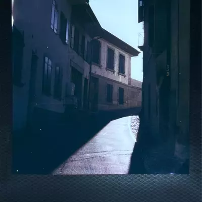 Narrow cobblestone street in Moudon's upper town with old stone buildings and dramatic shadows