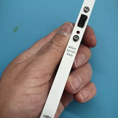 Allen Synthesis USB router module (usbr) held in hand, showing the white front panel with USB port and red LED