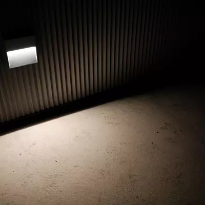 Light streaming through opening in wooden slatted wall, projecting geometric shadows on concrete floor