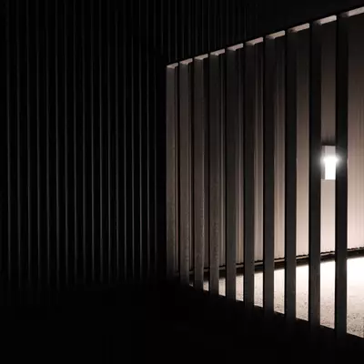 Perspective view of vertical wooden slats with light filtering through, casting shadows on the floor