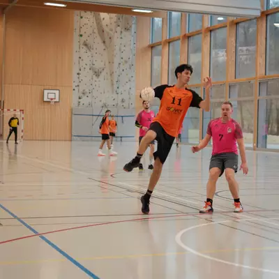 Joueur numéro 11 du HBC Moudon en orange courant avec le ballon, défendu par un joueur du RSB/Yverdon numéro 7 en rose