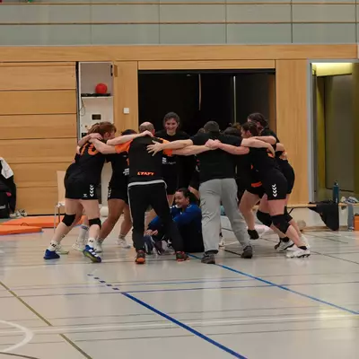 L'équipe du HBC Moudon formant un cercle sur le terrain après le match, joueuses et staff se tenant par les épaules dans un moment de cohésion