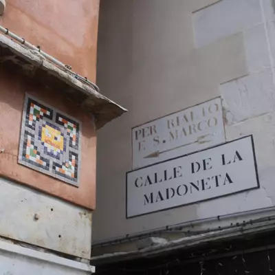 Space Invader mosaic tile artwork on a terracotta wall beside a 
