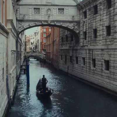 Gondola passing beneath the Bridge of Sighs on a narrow canal between historic stone buildings in Venice