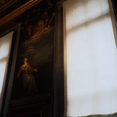 Interior of the Doge's Palace in Venice, a large baroque painting of a woman between white curtains filtering sunlight, gilded ceiling visible above