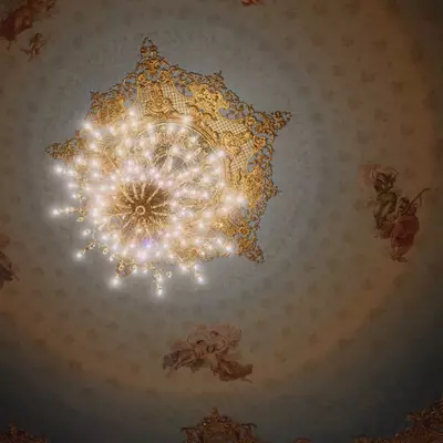 Ceiling of Teatro La Fenice opera house in Venice, a gilded chandelier at the centre of a painted dome with angels and cherubs