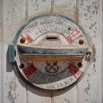 A weathered circular metal plaque mounted on a white wooden door, labeled 