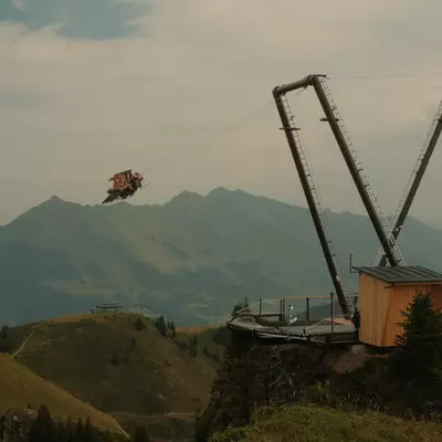 Riders suspended in mid-air on the Balanc'Air, a giant swing installed at 2,110 m altitude on the summit of Grand Chamossaire, with the Vaudois Alps in the background.