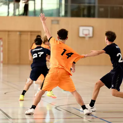 The player in the number 14 orange shirt is having his shirt pulled by a defender in black.