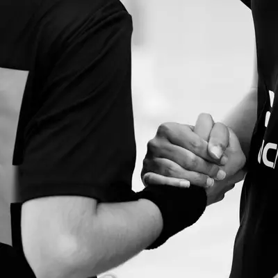 Deux joueuses de handball se serrent la main après le match, portant les maillots numérotés 4 et 6.