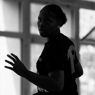 Joueuse de handball en tenue noire, main levée, se tenant prête sur le terrain lors du match contre Crissier.