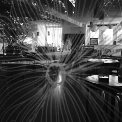 A black and white photo of the inside of a café. And the photo is taken through a window on which a flower is drawn.