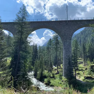 un pont ferroviaire composé de trois arches. Un torrent coule dessous
