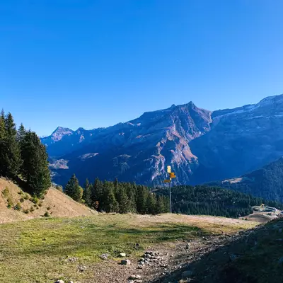 In the foreground, a hiking trail indicator. In the background, the Diablerets massif.