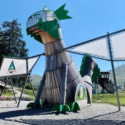 Un module de place de jeux qui est un dragon de 4m de haut dans lequel les enfants peuvent monter. Ses ailes sont composées de cordages où l'on peut grimper.