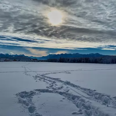 A snowy landscape with the sun behind the clouds