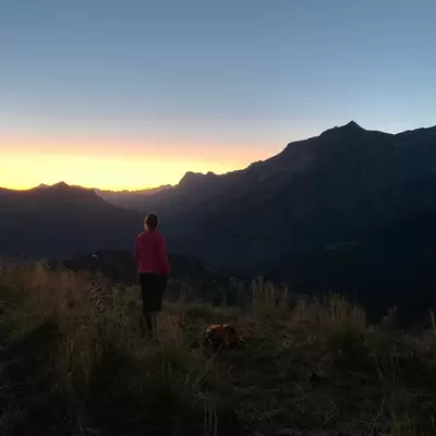 Le soleil se lève derrière les montagne. Au premier plan Céline dans la peine ombre le regarde