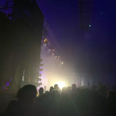 Chilla en concert dans le Club Tent. la photo est prise depuis le côté gauche de la scène. L'artiste Chilla est sur la scène à gauche à contre-jour. Le public est éclairé par les projecteurs sur la droite.