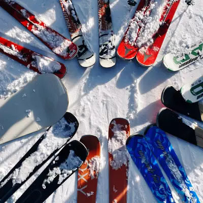 Nine pairs of skis and a snowboard in a circle, taken from above.
